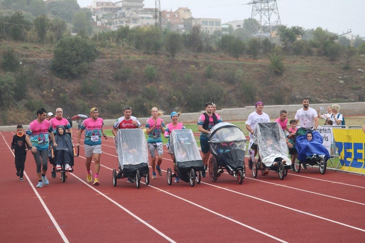 Participantes de la Rett Race empujando sillas adaptadas en la pista de atletismo de Sant Boi